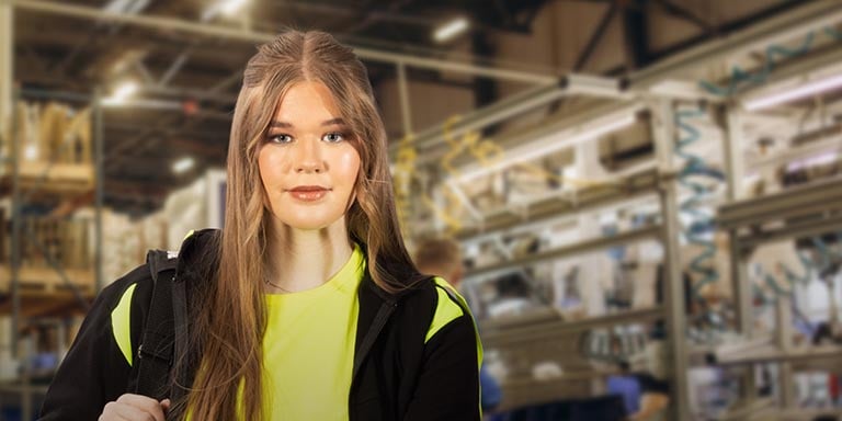 En kvinna iklädd varselkläder som bär på utrustning