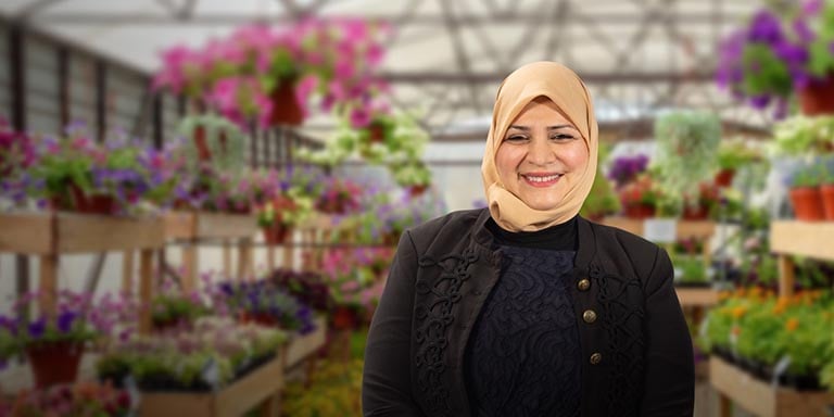 En kvinna i svarta kläder står i en blomsterodling