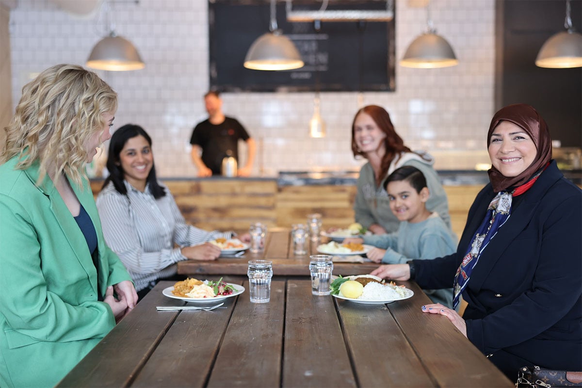 Fyra kvinnor och en pojke sitter vid ett bord på en restaurang och äter