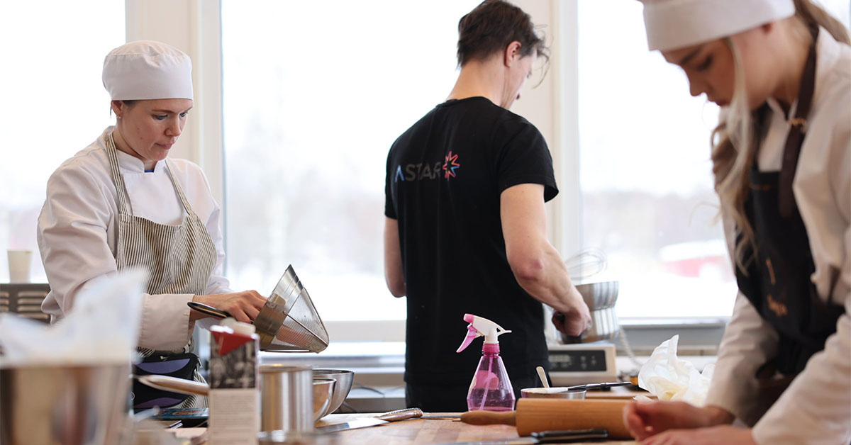 Tre elever från Astar iklädda bagaruniform bakar