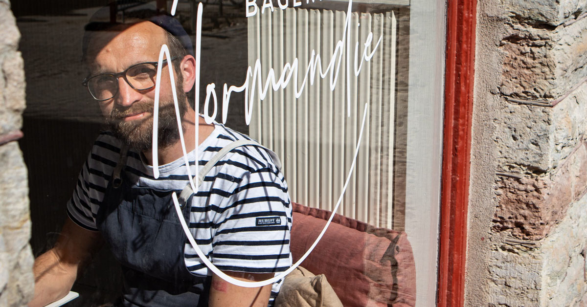 Serge Le Normand tittar ut genom ett fönster på sitt café Bageri Normandie